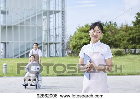 Stock Photograph - Japanese caretakers helping senior patient. Fotosearch