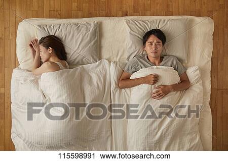 Stock Image - Japanese couple in bed. Fotosearch