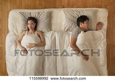 Stock Image - Japanese couple in bed. Fotosearch