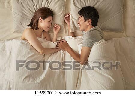 Stock Image - Japanese couple in bed. Fotosearch