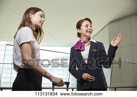 Picture - Japanese Flight Attendant helping customer. Fotosearch