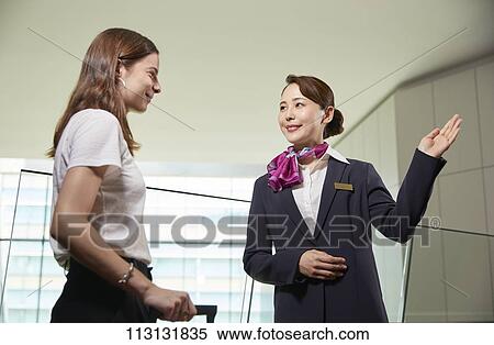 Stock Photography - Japanese Flight Attendant helping customer. Fotosearch