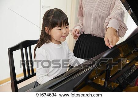 Picture - Japanese kid practicing piano. Fotosearch