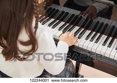 Stock Image - Japanese kid practicing piano. Fotosearch