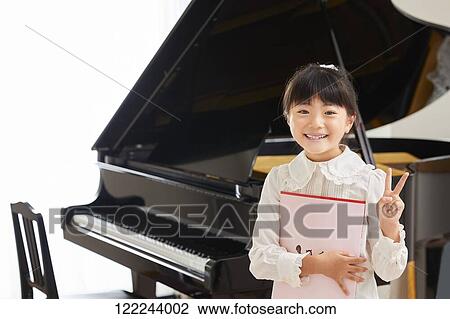 Stock Image - Japanese kid practicing piano. Fotosearch