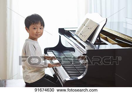 Stock Image - Japanese kid practicing piano. Fotosearch