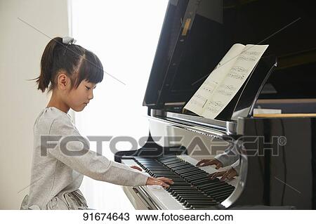 Stock Image - Japanese kid practicing piano. Fotosearch