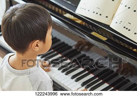 Stock Photograph - Japanese kid practicing piano. Fotosearch
