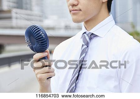 Stock Image - Japanese man with portable fan. Fotosearch