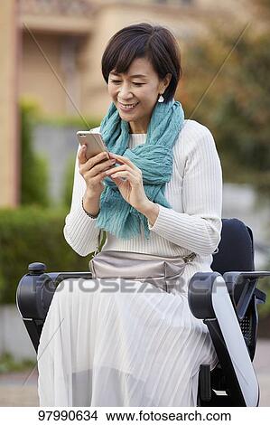 Picture - Japanese senior woman on electric wheelchair. Fotosearch