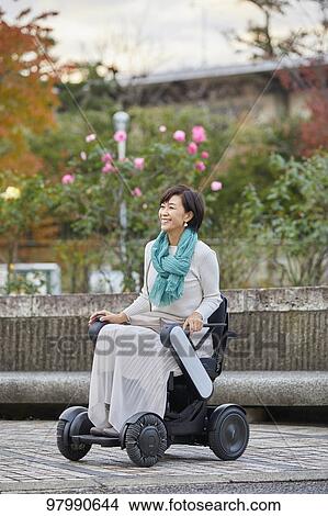 Picture - Japanese senior woman on electric wheelchair. Fotosearch