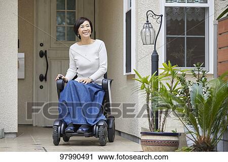 Stock Image - Japanese senior woman on electric wheelchair. Fotosearch