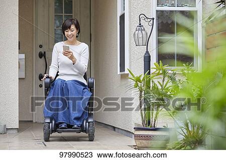 Stock Image - Japanese senior woman on electric wheelchair. Fotosearch