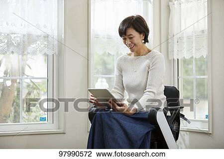 Stock Image - Japanese senior woman on electric wheelchair. Fotosearch