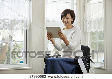 Stock Image - Japanese senior woman on electric wheelchair. Fotosearch