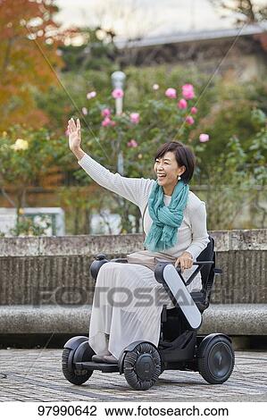 Stock Image - Japanese senior woman on electric wheelchair. Fotosearch