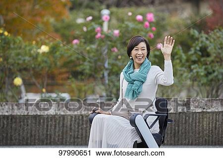 Stock Image - Japanese senior woman on electric wheelchair. Fotosearch