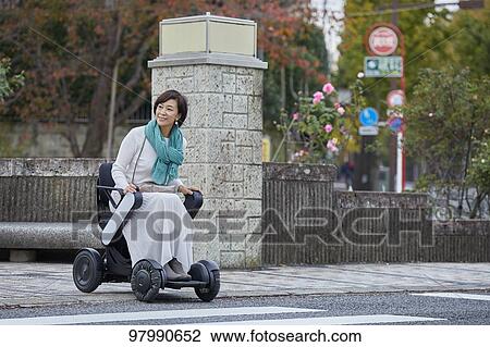 Stock Image - Japanese senior woman on electric wheelchair. Fotosearch