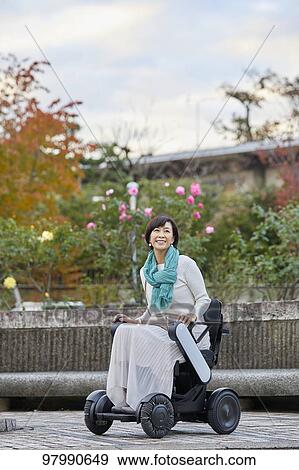 Stock Photo - Japanese senior woman on electric wheelchair. Fotosearch