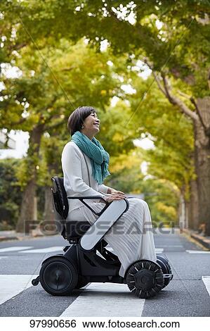 Stock Photograph - Japanese senior woman on electric wheelchair. Fotosearch