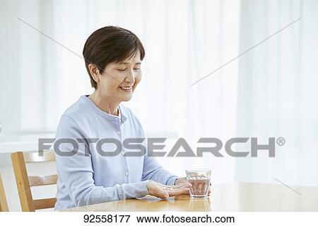 Stock Photo - Japanese senior woman taking pills. Fotosearch