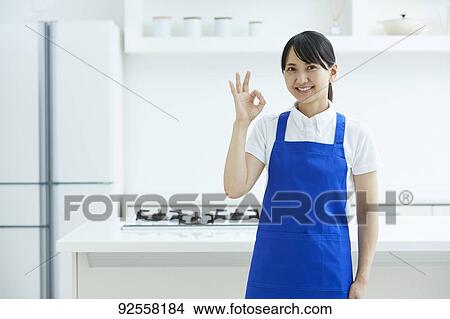 Picture - Japanese woman wearing apron at home. Fotosearch