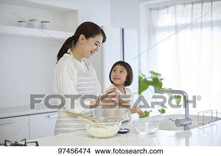 Picture - Japanese woman with daughter in the kitchen. Fotosearch