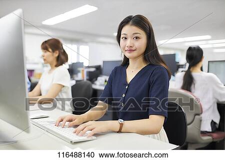 Stock Image - Japanese woman working in the office. Fotosearch