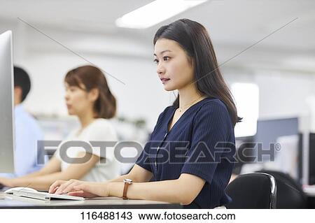 Stock Image - Japanese woman working in the office. Fotosearch