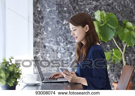 Picture - Japanese woman working remotely. Fotosearch