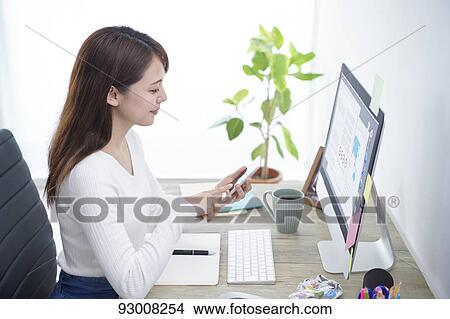 Picture - Japanese woman working remotely. Fotosearch