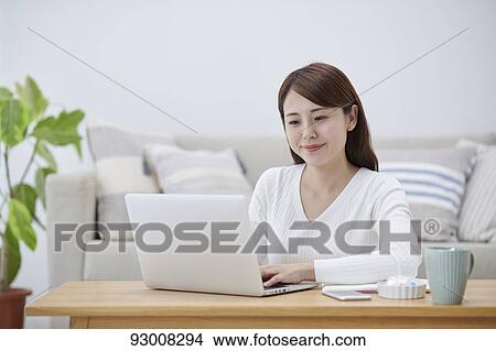 Picture - Japanese woman working remotely. Fotosearch
