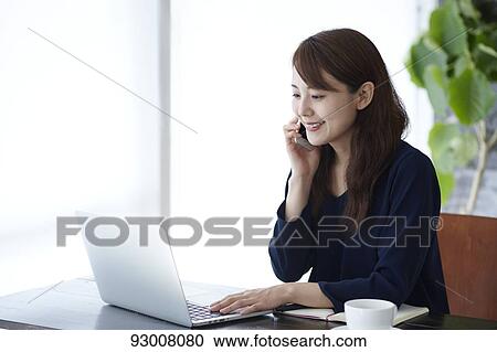 Stock Image - Japanese woman working remotely. Fotosearch