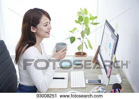 Stock Image - Japanese woman working remotely. Fotosearch