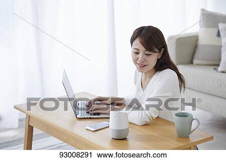 Stock Image - Japanese woman working remotely. Fotosearch