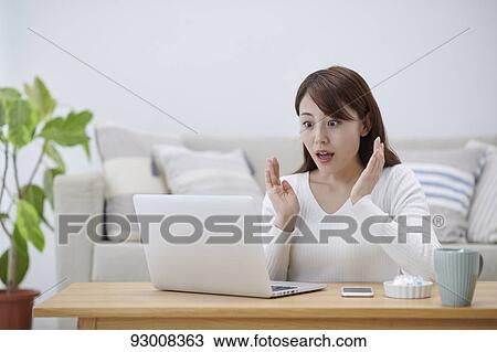 Stock Image - Japanese woman working remotely. Fotosearch