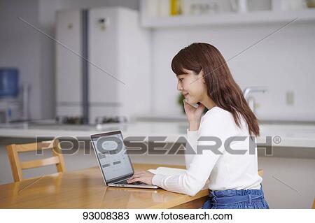 Stock Image - Japanese woman working remotely. Fotosearch