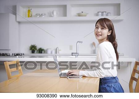 Stock Image - Japanese woman working remotely. Fotosearch