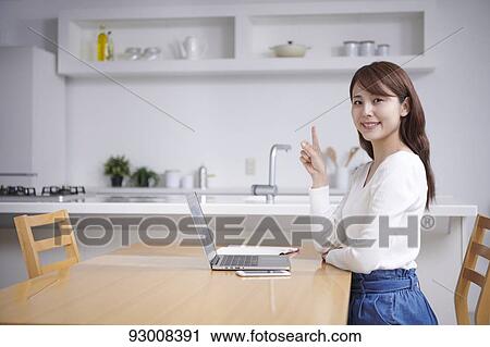 Stock Image - Japanese woman working remotely. Fotosearch