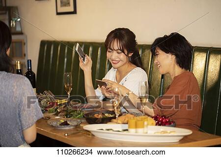 Picture - Japanese women happily dining together. Fotosearch