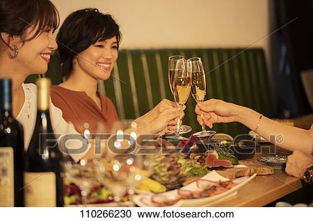 Stock Image - Japanese women happily dining together. Fotosearch
