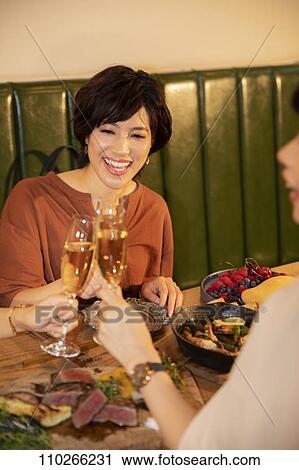 Stock Image - Japanese women happily dining together. Fotosearch