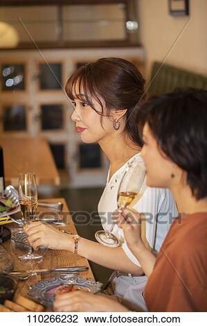 Stock Image - Japanese women happily dining together. Fotosearch