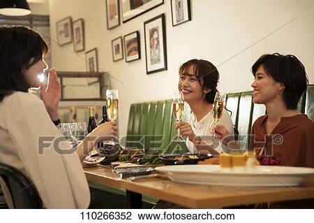 Stock Image - Japanese women happily dining together. Fotosearch