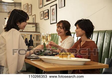 Stock Image - Japanese women happily dining together. Fotosearch