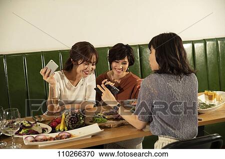 Stock Image - Japanese women happily dining together. Fotosearch
