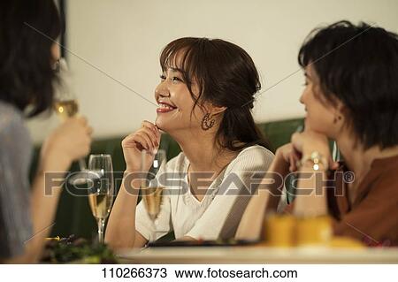 Stock Image - Japanese women happily dining together. Fotosearch