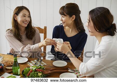 Stock Image - Japanese women having home party. Fotosearch
