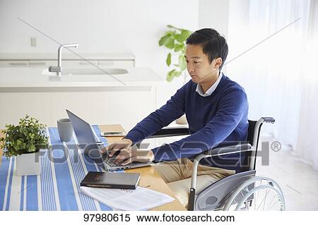 Stock Photography - Japanese young man on wheelchair working from home. Fotosearch