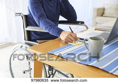 Stock Photography - Japanese young man on wheelchair working from home. Fotosearch